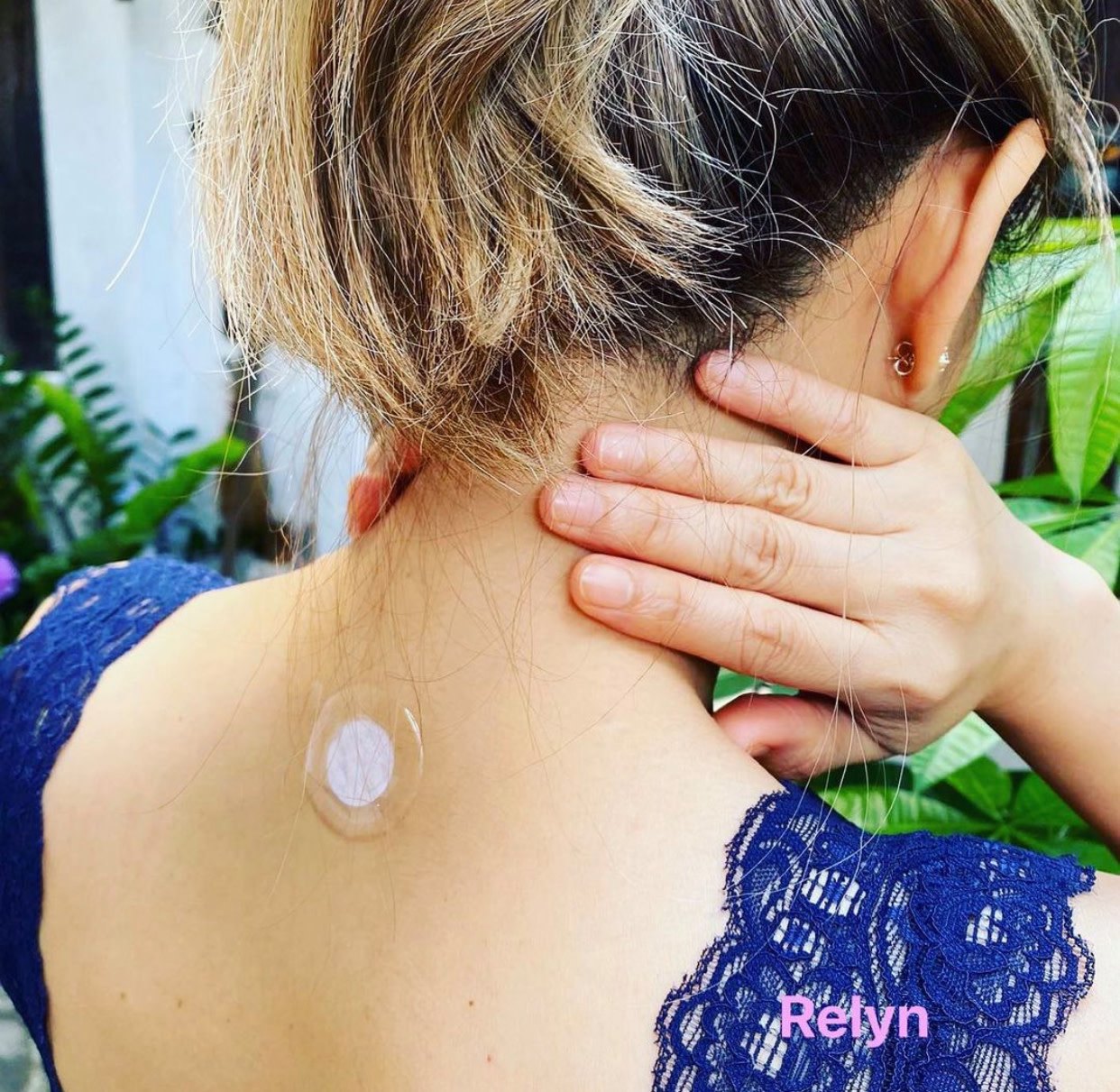 Woman applying neck patch, blue lace dress detail