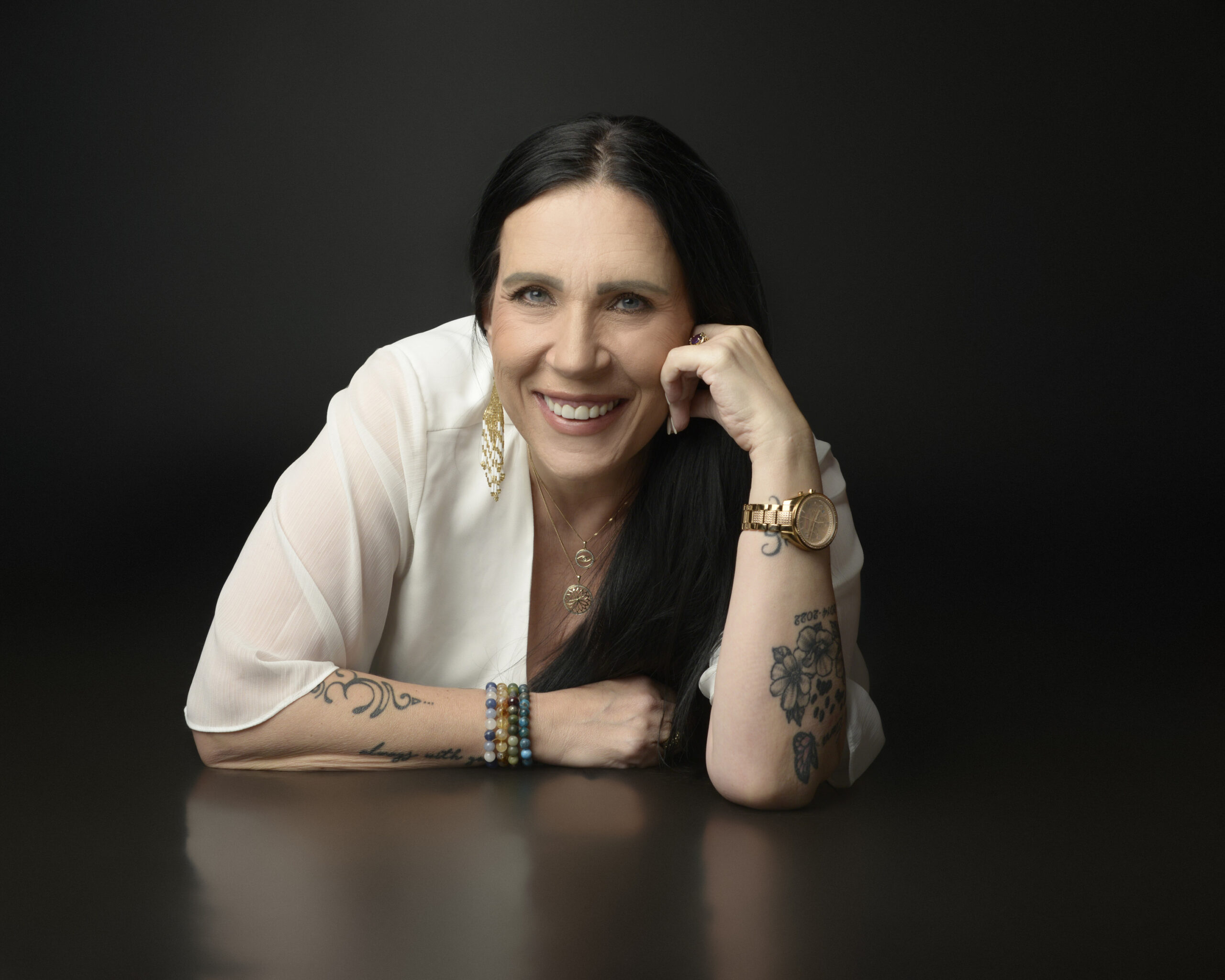 Smiling woman with tattoos posing in white blouse